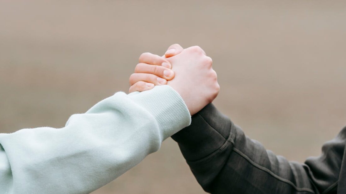 Two adults holding hands in an outdoor park setting, symbolizing trust and connection.